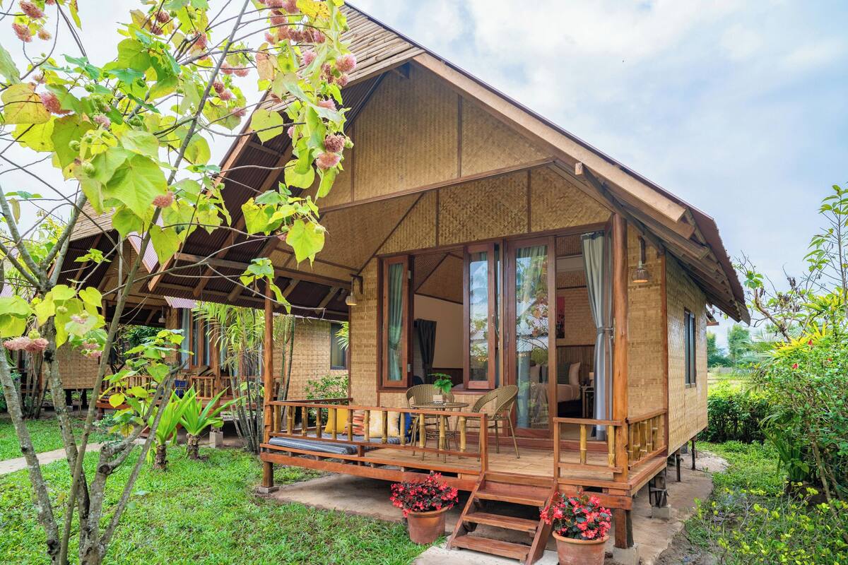 A wooden house with a porch, large windows, and a garden.