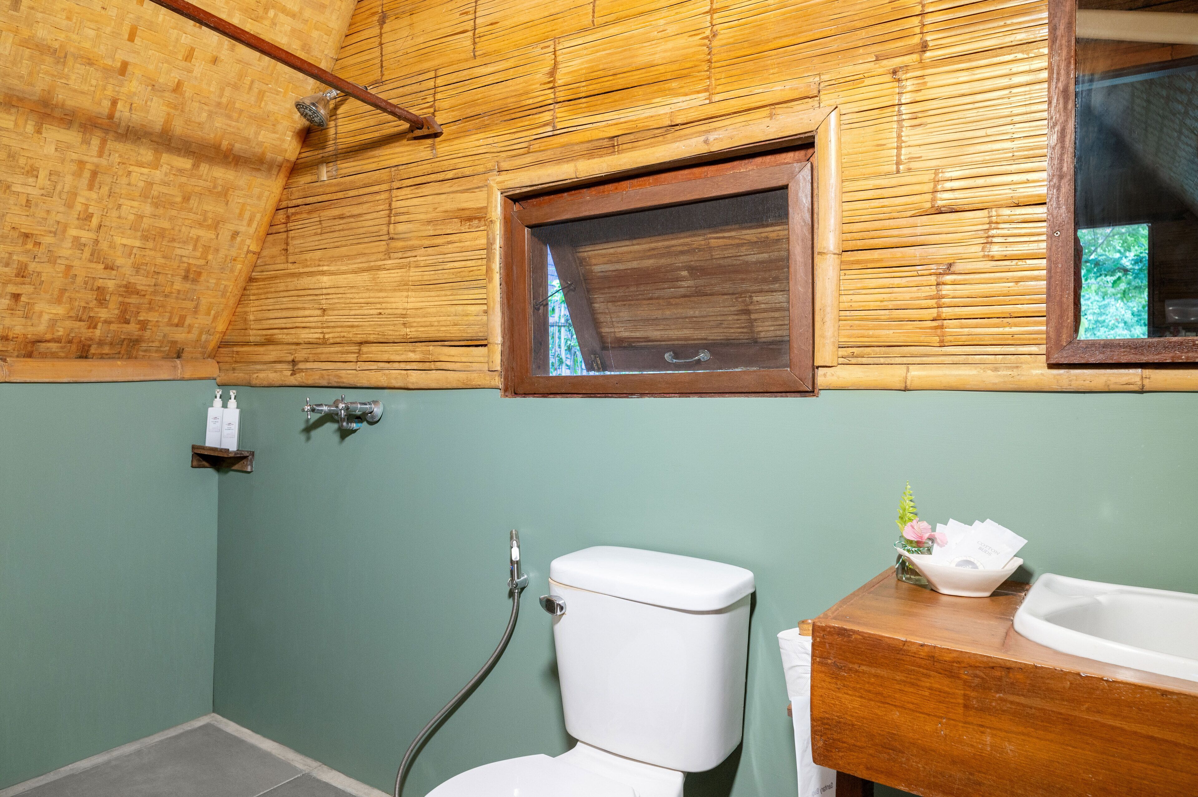 A bathroom with a wooden ceiling, a toilet, a sink, and a window.