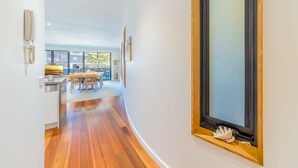 Un intérieur moderne avec un plancher en bois, un coin repas comprenant une table et des chaises, et une grande fenêtre donnant sur l’extérieur.