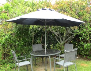 Relax in a serene garden setting with a shaded table and comfortable seating for four.