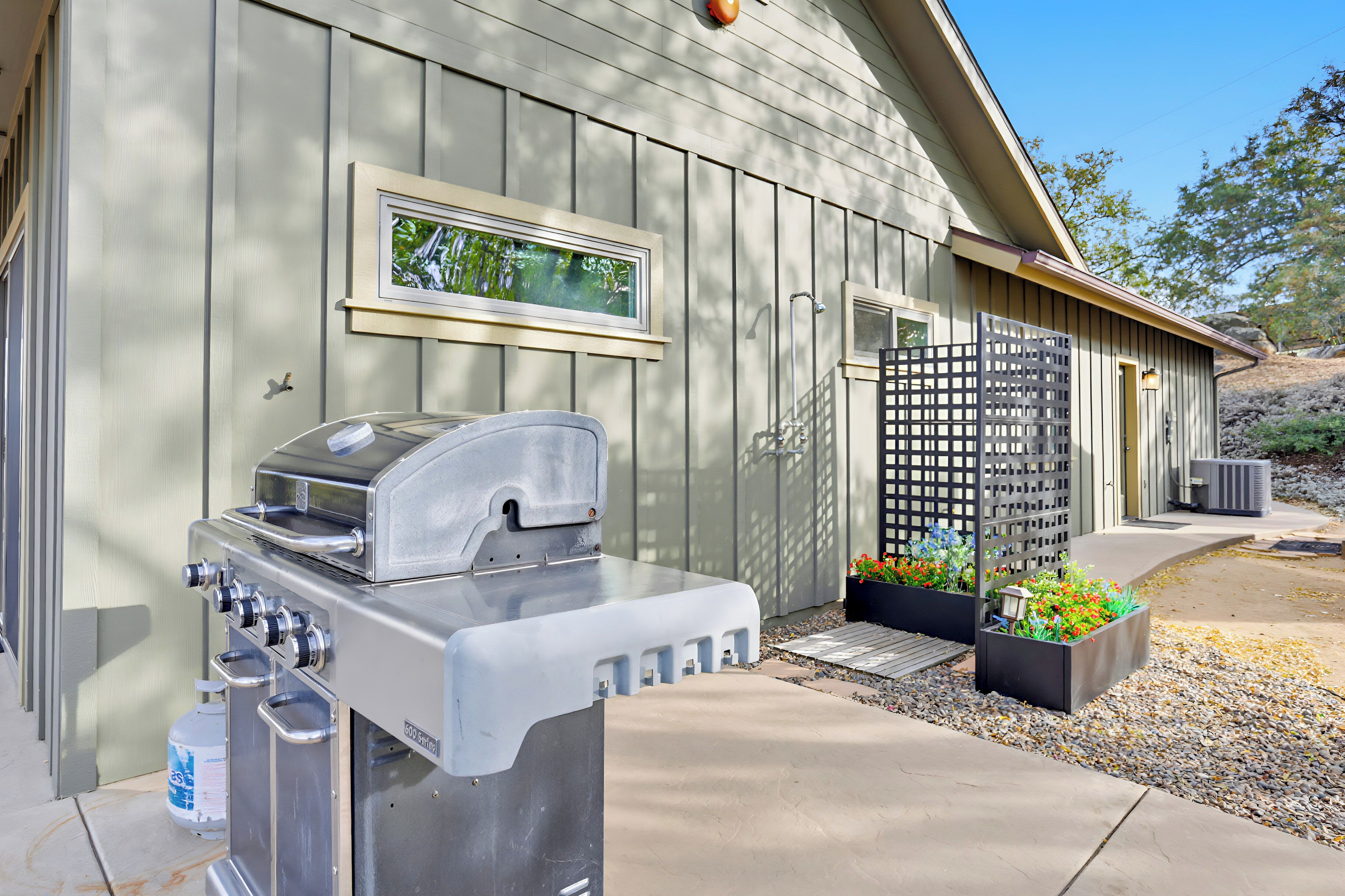 Un barbecue et un distributeur d’eau se trouvent à l’extérieur d’un bâtiment qui possède une fenêtre et une porte.