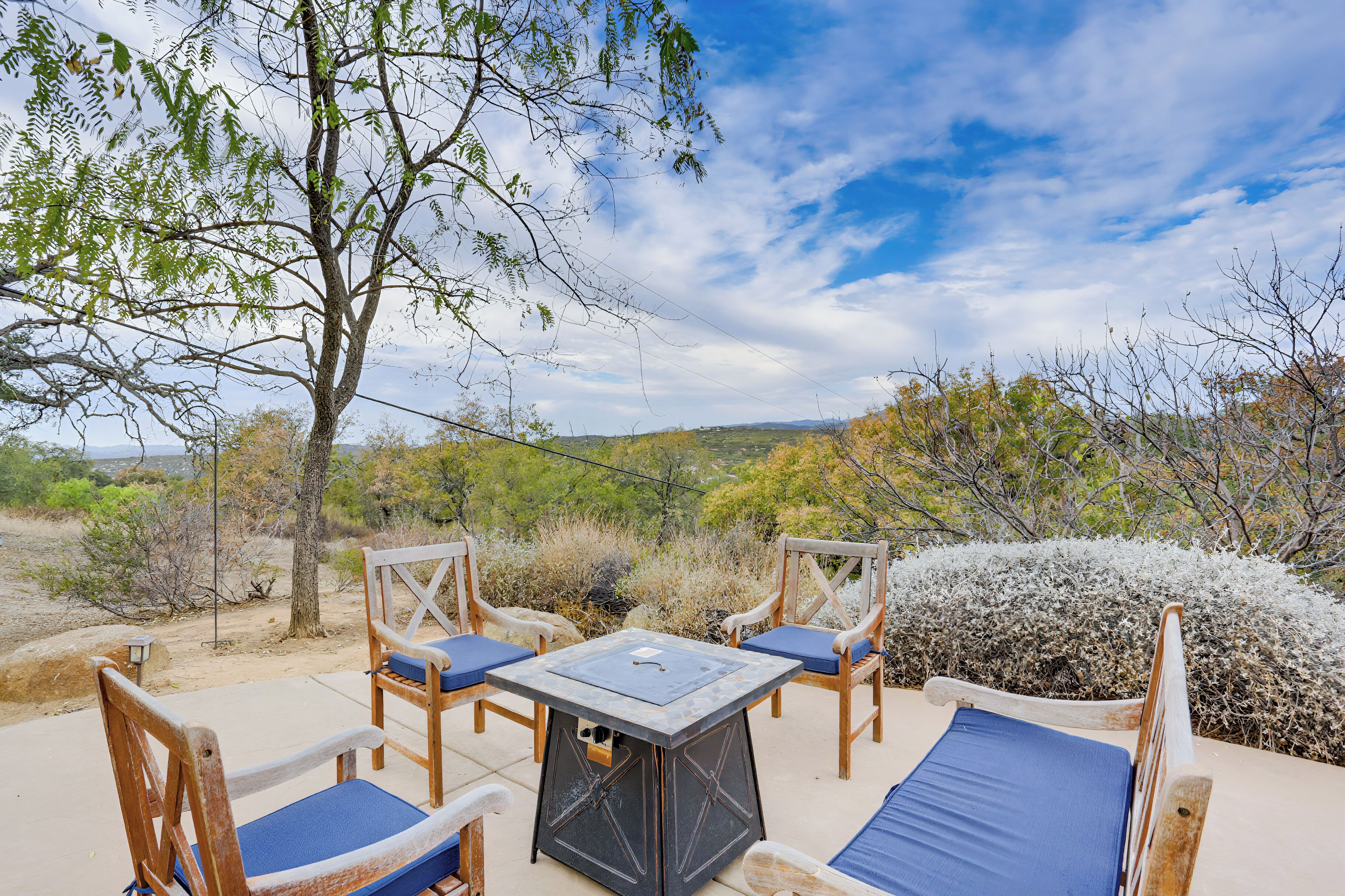 An outdoor seating area with a table and chairs, surrounded by natural scenery and a clear sky.