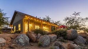 Una casa moderna con un porche, rocas grandes y un paraguas rojo.
