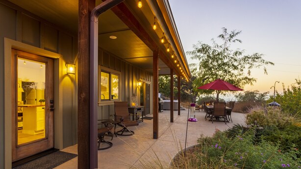 Un patio cubierto al aire libre con asientos y comedor, una puerta de madera y un interior bien iluminado.