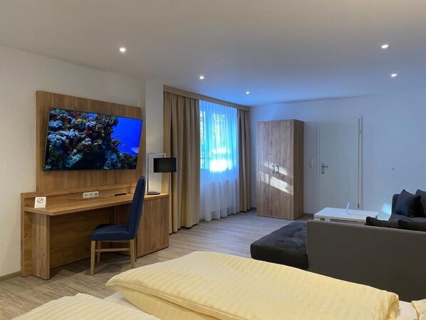 Una habitación de hotel con una cama, un escritorio, un televisor y un sofá.