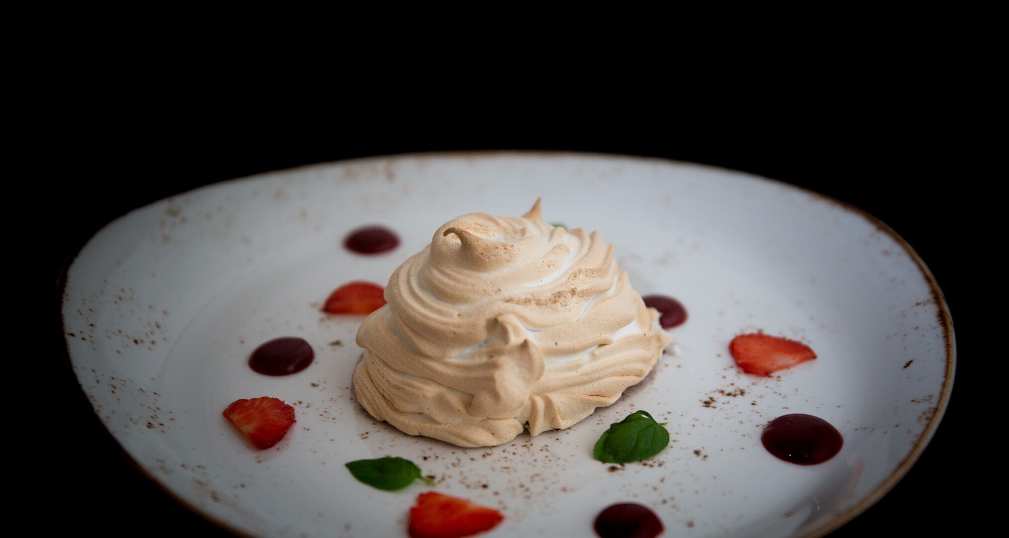 Un dessert su un piatto con fragole e una foglia di menta.