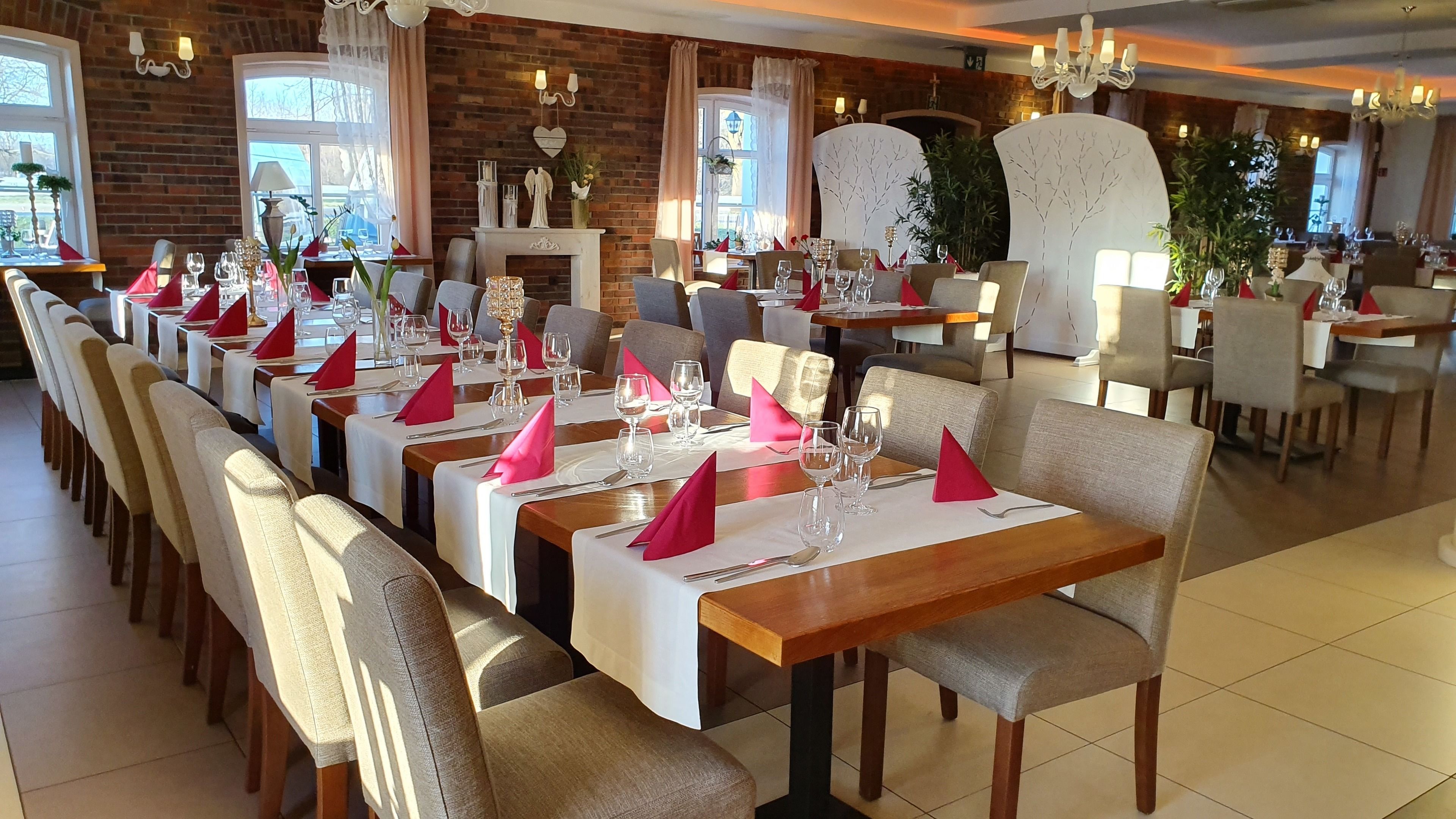 Een restaurant met lange tafels, stoelen en rode servetten.