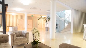 A spacious lobby with a grand staircase, plush seating, and a potted orchid centerpiece. - Nadodrzański Dwór (Nowa Sól)