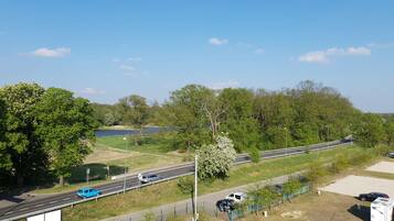 A highway with a pedestrian bridge, trees, and a body of water in the background.