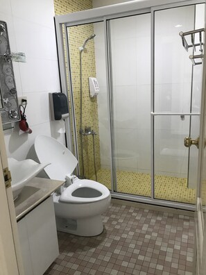 A bathroom with a toilet, a glass-enclosed shower, and a soap dispenser on the wall. - Zhu Yuan Homestay (Zhuqi)
