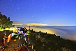 A hotel with a rooftop terrace, a parking area, and a view of the surrounding forest. - Zhu Yuan Homestay (Zhuqi)