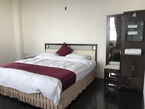 A neatly made bed with white linens and a maroon throw, a wooden nightstand with a lamp, and a dark wooden wardrobe with a mirror. - Zhu Yuan Homestay (Zhuqi)