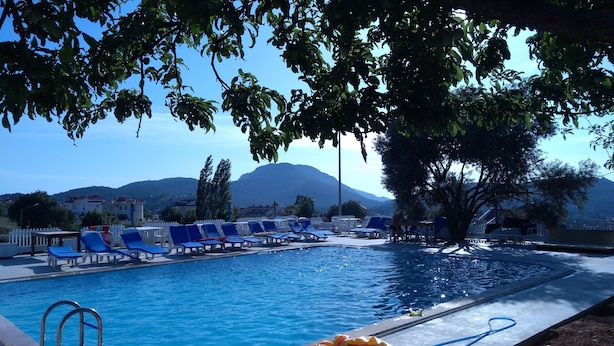 A swimming pool with blue lounge chairs and a mountain in the background.