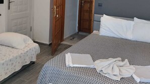 A bedroom with a large bed, a smaller bed, and a wooden door.