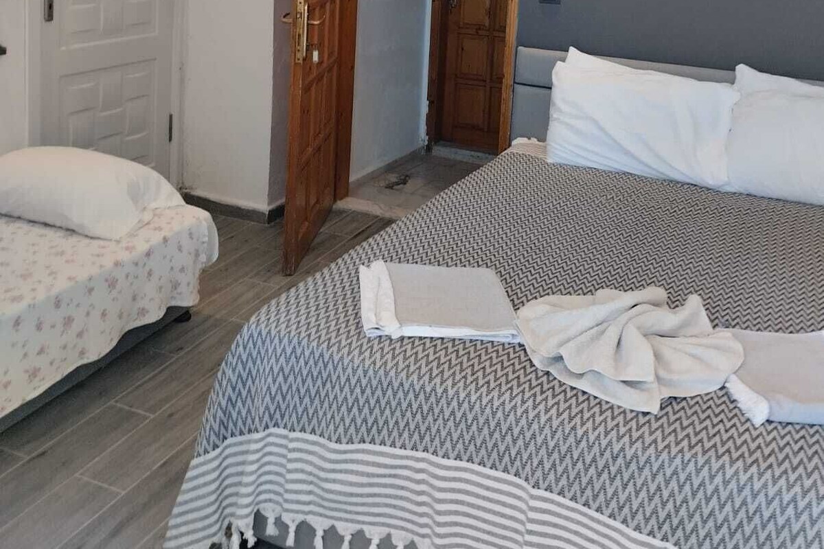 A bedroom with a large bed, a smaller bed, and a wooden door.