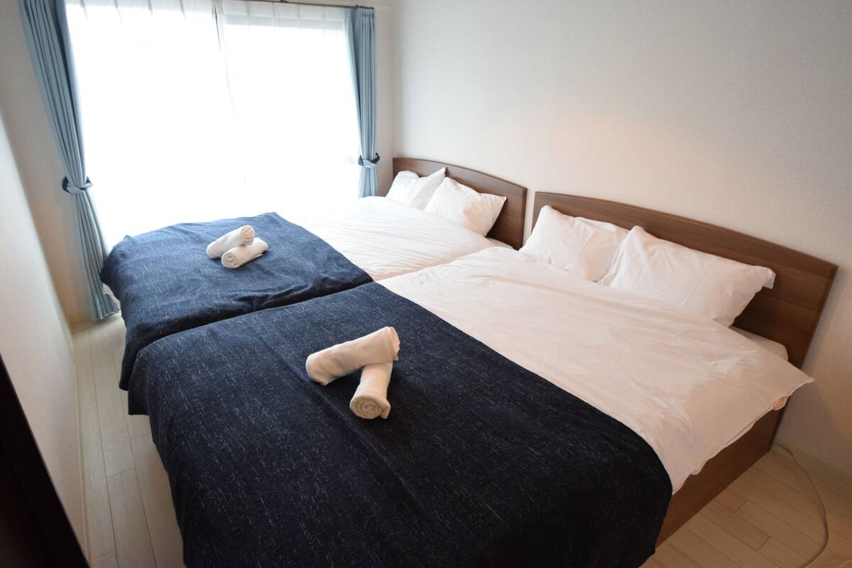A double room with two beds, each with a dark blue bedspread and white pillows.
