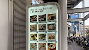 Un panneau affichant le menu des restaurants et des cafés, avec différentes options de plats et les heures d’ouverture.