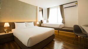 Una habitación de hotel con una cama grande, una cama más pequeña, un escritorio y una silla.
