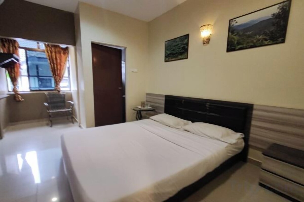 A hotel room with a bed, a chair, a small table, and a door.