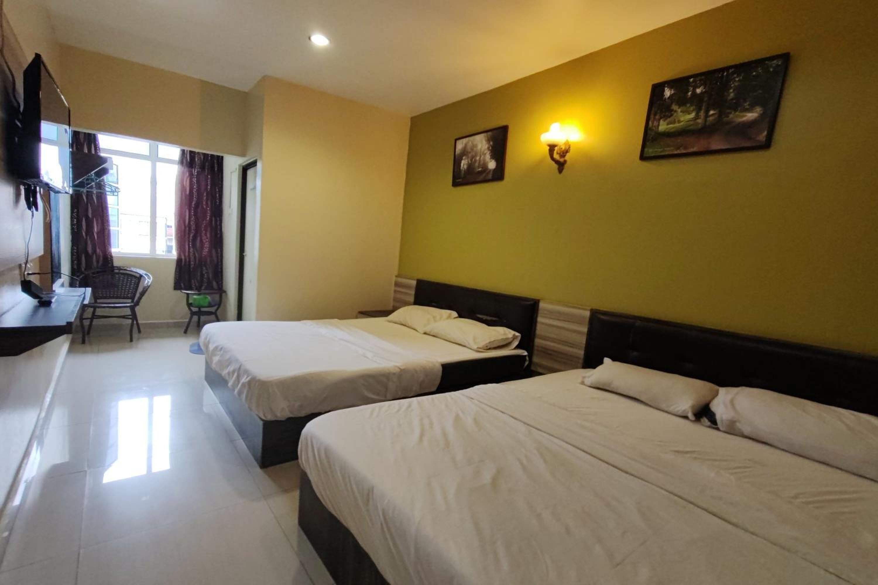 A hotel room with two beds, a desk, a chair, and a window with curtains.