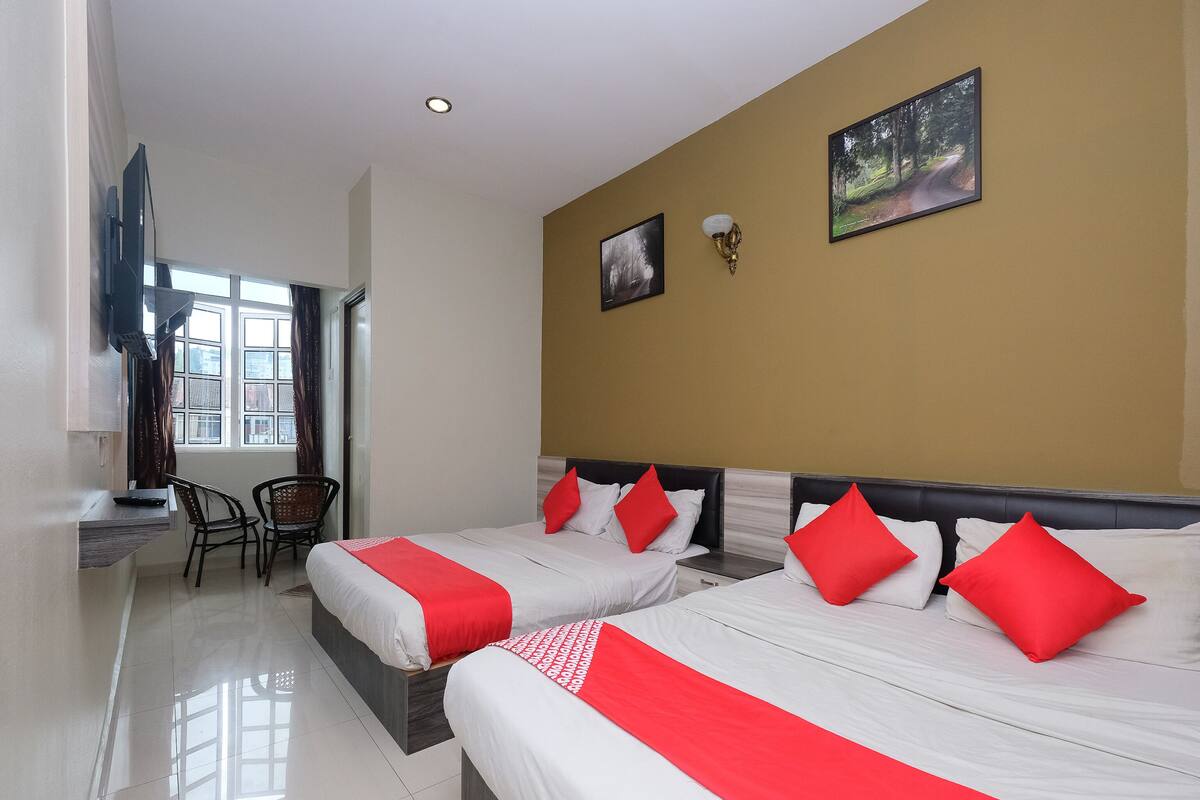 A hotel room with two beds, a desk, and a chair.