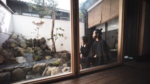 A room with a large window overlooking a rock garden and a traditional Japanese-style building. - Modern Machiya MIBU (Kyoto)