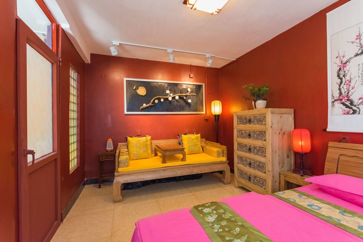 A room with a sofa, a bed, a cabinet, and a painting on the wall.