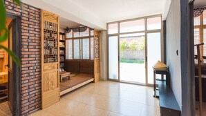 Una habitación amplia con una librería de madera tradicional, un banco acolchado y un ventanal corredero que da a un espacio exterior.