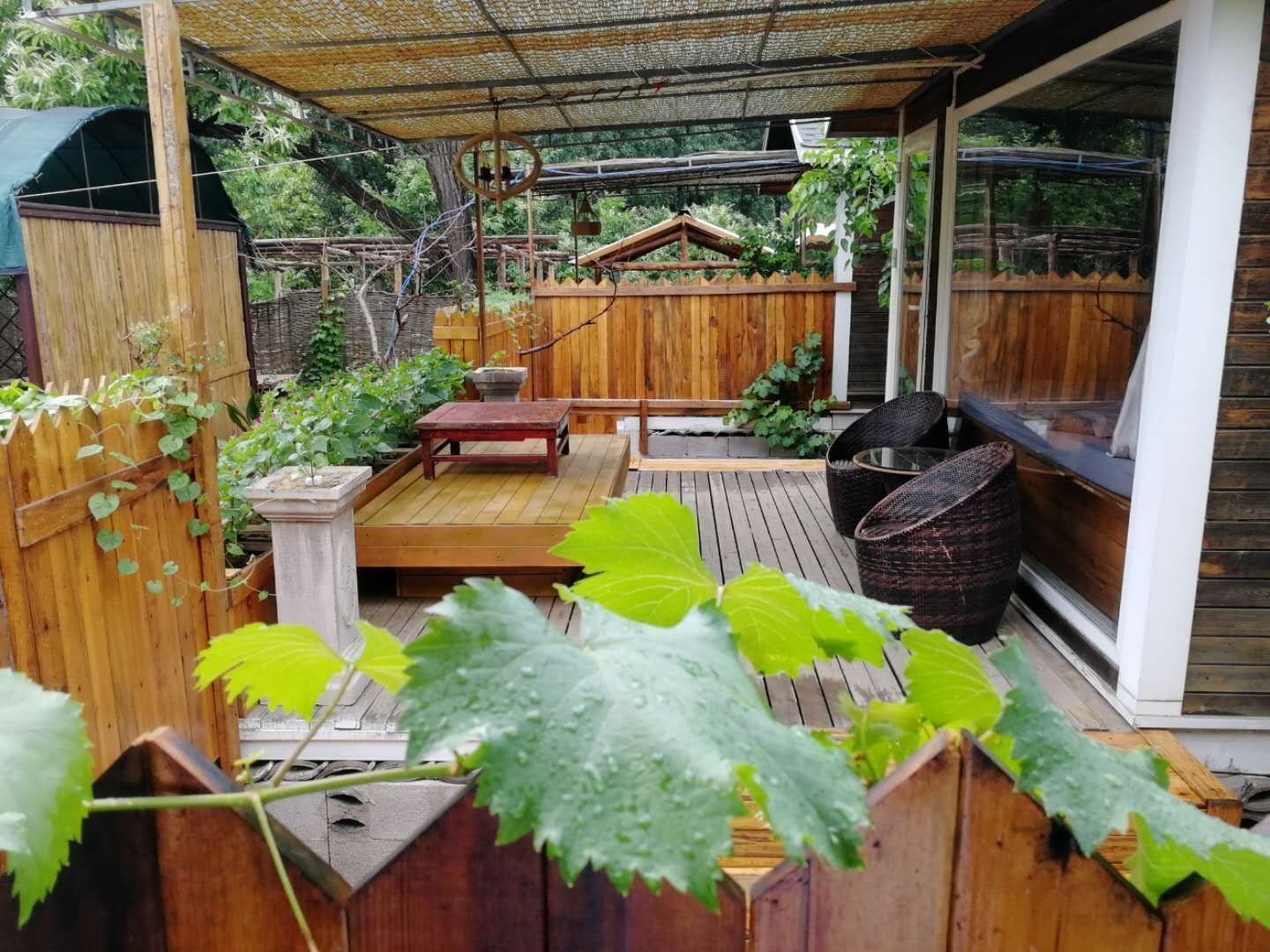 Una terraza de madera con una pérgola, un área de estar y vistas a la vegetación circundante.