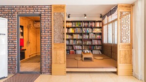 Una habitación con pared de ladrillo, una estantería de madera y un rincón con esteras de tatami.