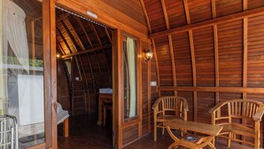 A wooden interior with a dining table and chairs, a bench, and a wooden ceiling. - Sukawati Inn (Penida Island)