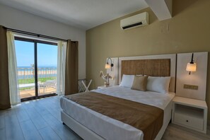 A hotel room with a large bed, a nightstand, a lamp, a view of the beach, and an air conditioning unit. - Ayvalık Sea Resort (Ayvalik)