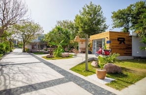 A modern building with a wooden facade, a paved walkway, and outdoor seating. - Ayvalık Sea Resort (Ayvalik)