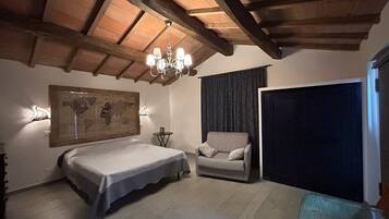 Ein Schlafzimmer mit Bett, Sessel, einer Karte an der Wand, einer Chandelüster und einem großen Fenster.