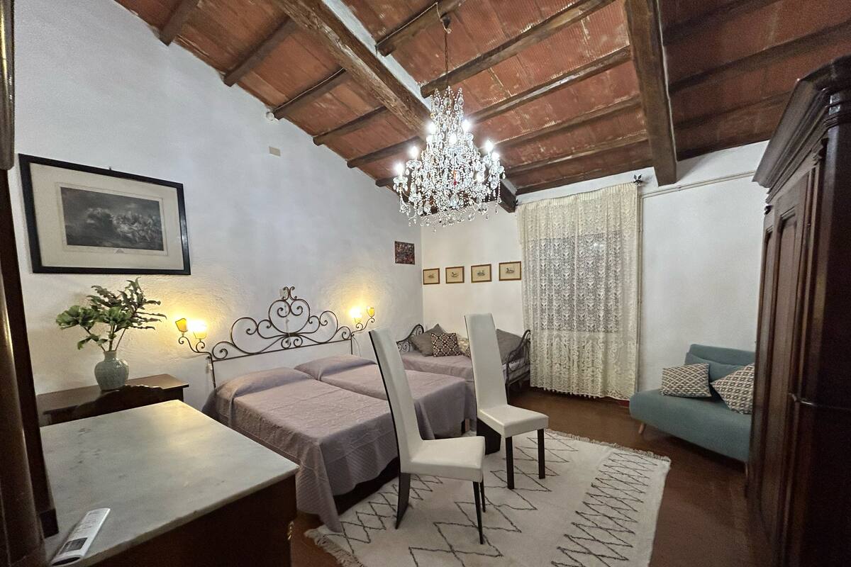 Un dormitorio con dos camas, un escritorio, una silla, una araña y un sofá.