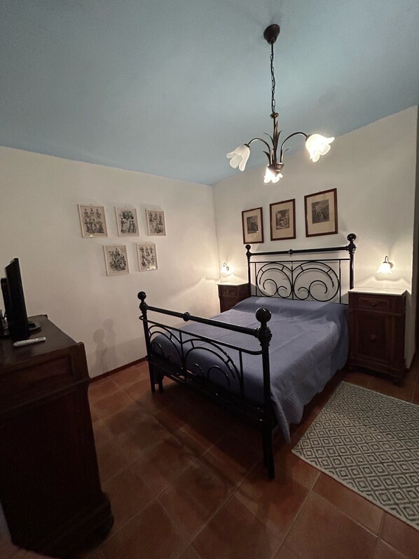 Un dormitorio con cama, cómoda, mesita de noche, lámpara y candelabro.