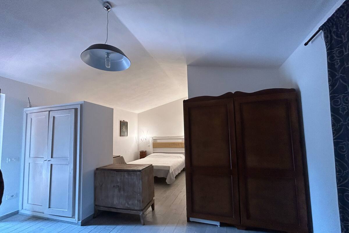 Un dormitorio con cama, armario y un pequeño cofre de madera.