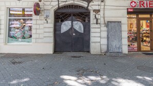 Fachada con una puerta metálica grande y ornamentada y un letrero encima.