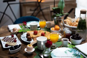 Une table de petit-déjeuner avec divers aliments, notamment des viennoiseries, des fruits et des boissons.