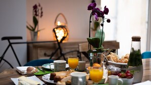 Een ontbijttafel met diverse soorten eten, waaronder gebak, fruit en een fles sap.