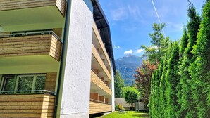 Ein modernes Gebäude mit Holzfassade, einem Balkon und Blick auf die Berge.