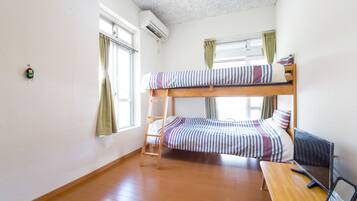 A bunk bed room with a wooden ladder, a desk, and a computer.