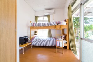 Habitación con literas, un escritorio, un televisor y una ventana con cortinas.