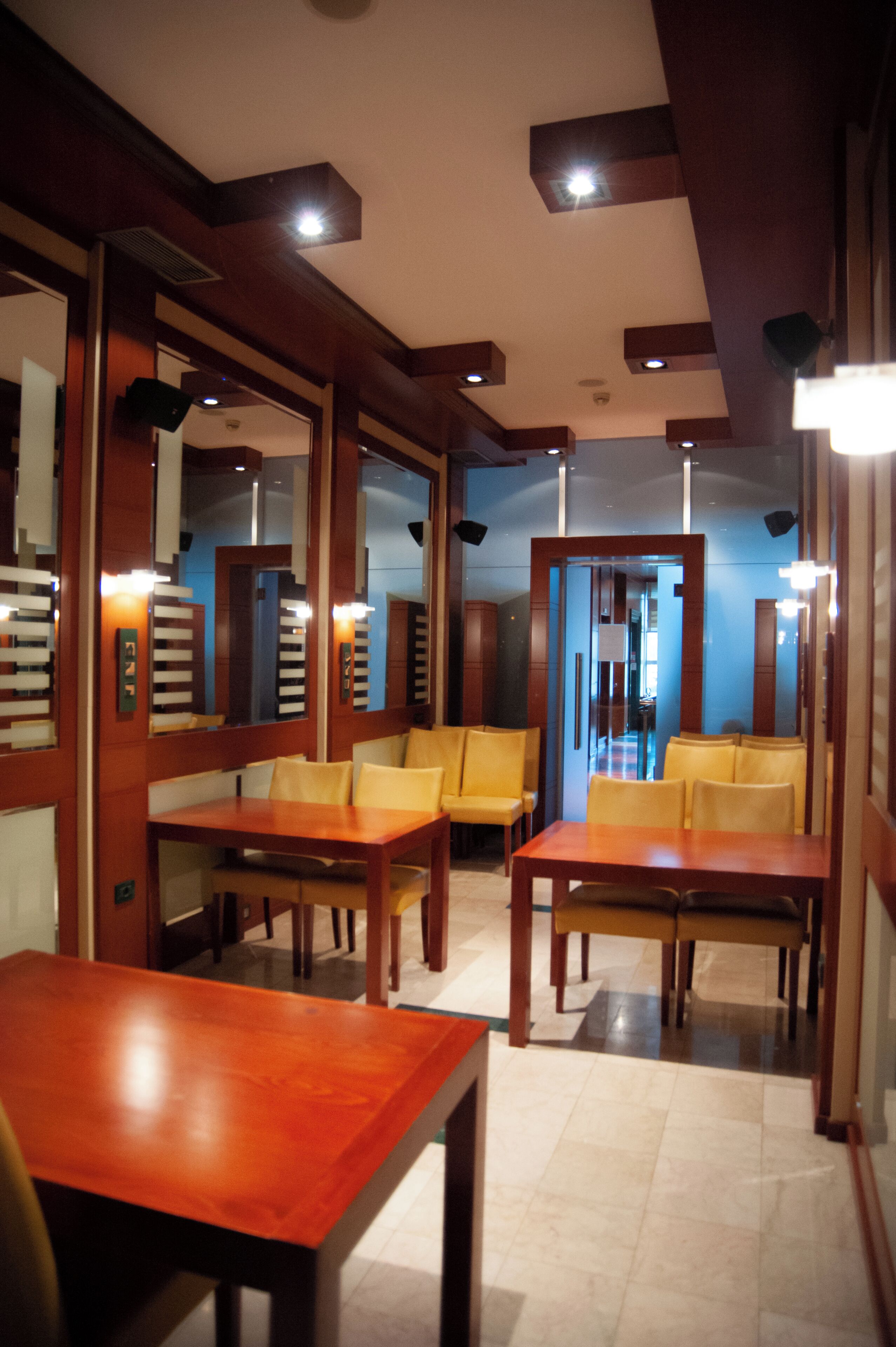 Un restaurant avec des tables et des chaises en bois, un mur bleu et un plafond doté d’un éclairage encastré.