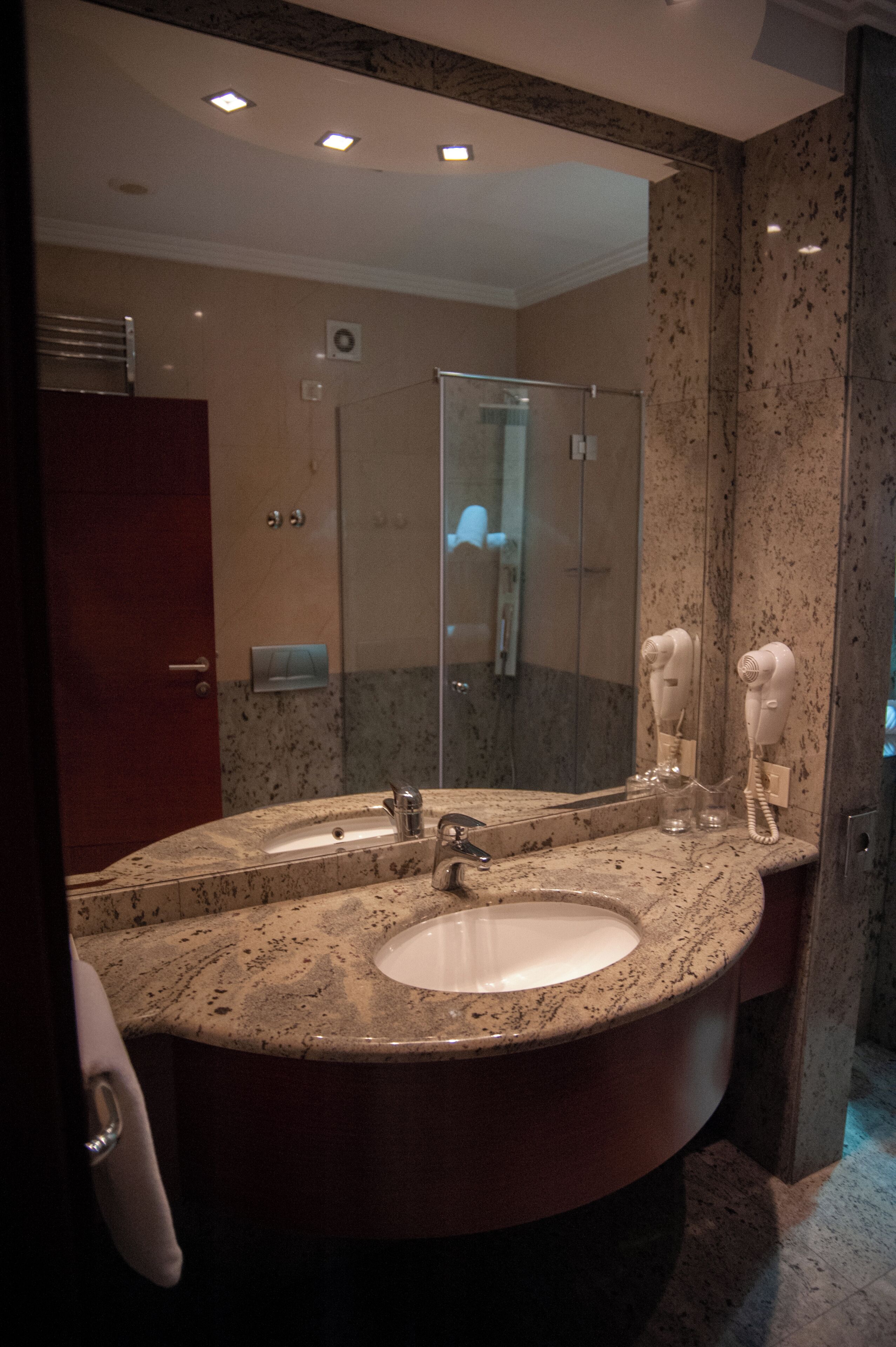 A bathroom with a double sink vanity, a mirror, a towel rack, and a hairdryer.