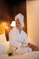 Una persona con bata blanca sentada en una cama con una botella de aceite de oliva.