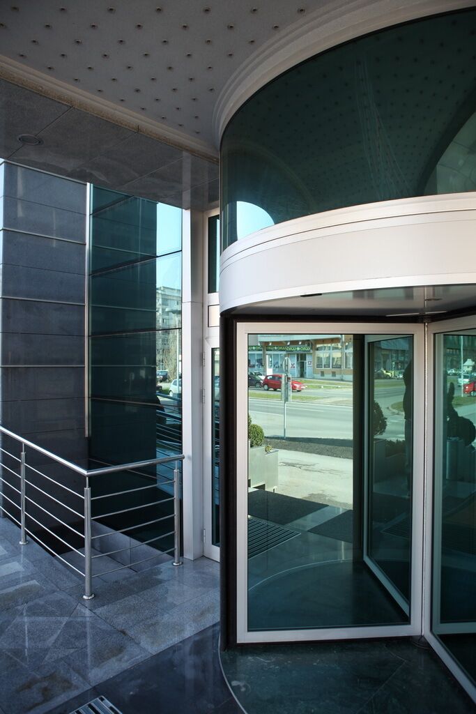 A modern building entrance with a glass door and a metal railing.