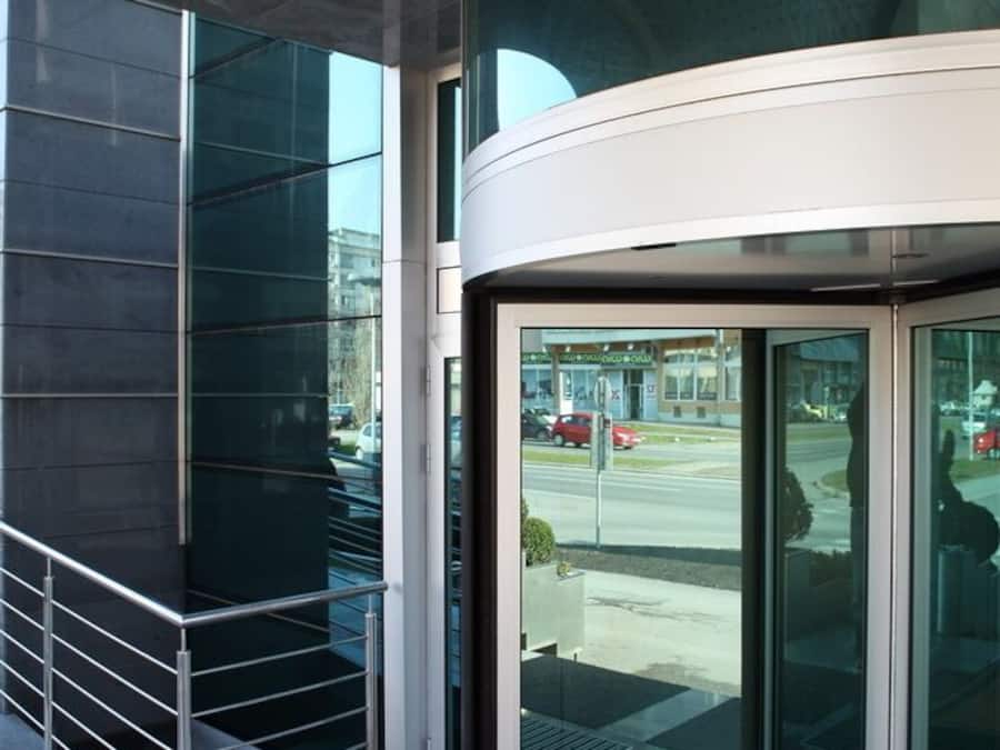 A modern building entrance with a glass door and a metal railing.