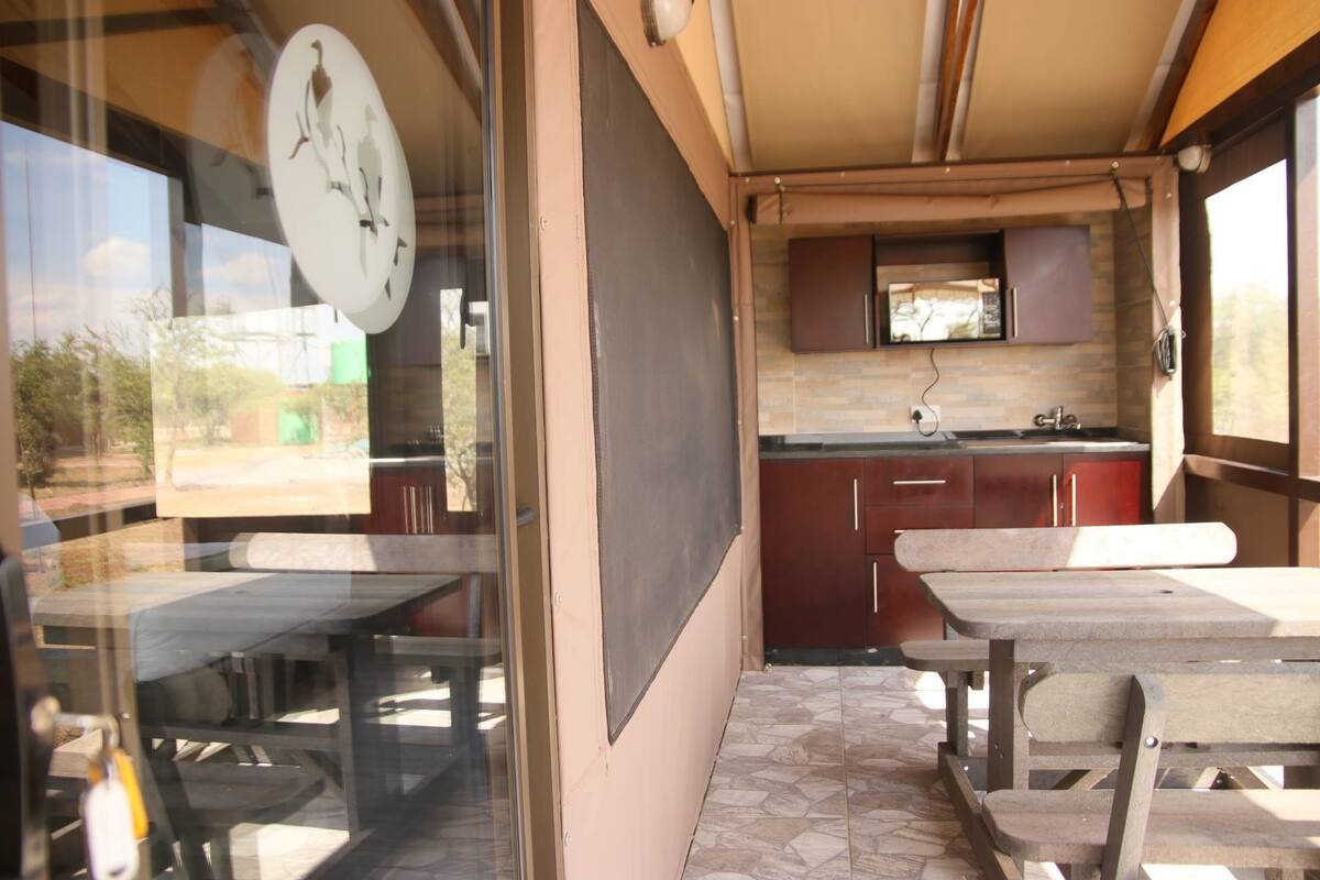Interior compacto de autocaravana con kitchenette, zona de comedor con mesa y bancos, y un ventanal con vistas al exterior.