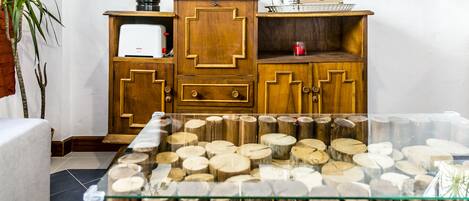 A wooden cabinet with drawers and shelves, a glass table with wooden logs, and a plant.